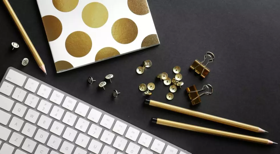 Workplace with keyboard and golden stationery